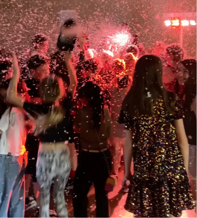 Children dancing at school disco with bright lights and foam